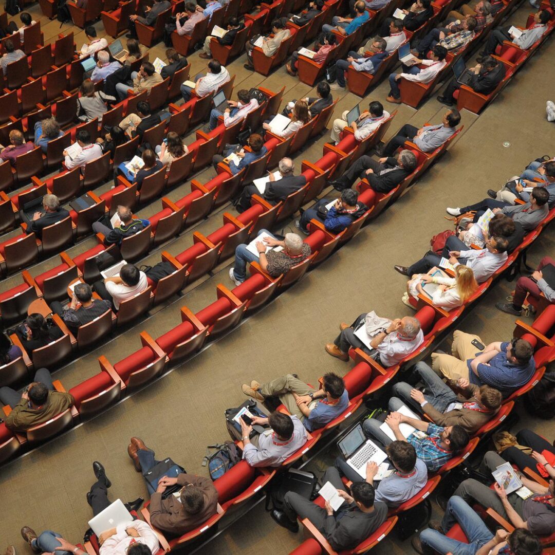 A group of people sitting in an auditorium, listening attentively.