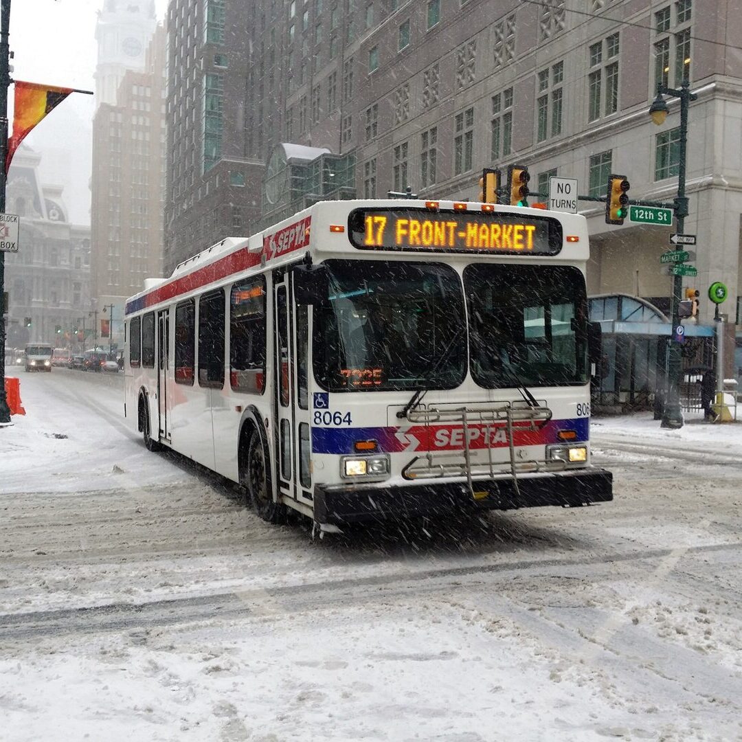 A city bus driving down a snow covered street.